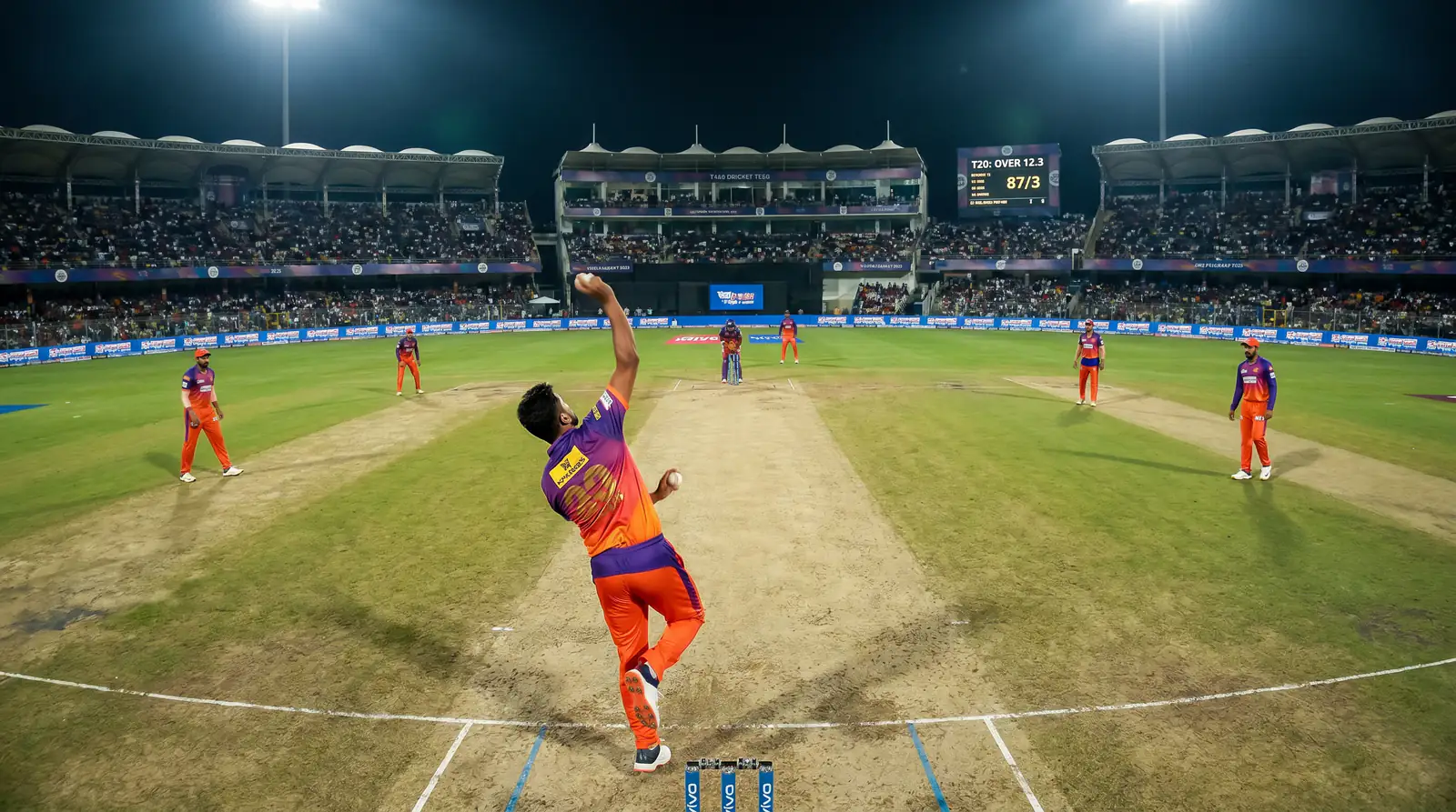 Spin bowler delivering during middle overs of a T20 with wide field placements